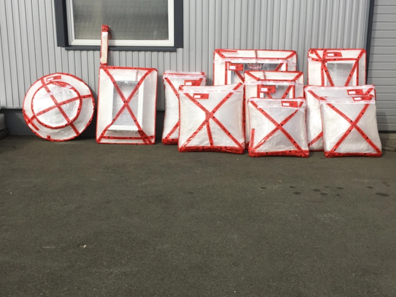 Reihe verpackter Lichtkuppeln mit roter Kantensicherung an der Hallenwand, darunter eine runde Kuppel.