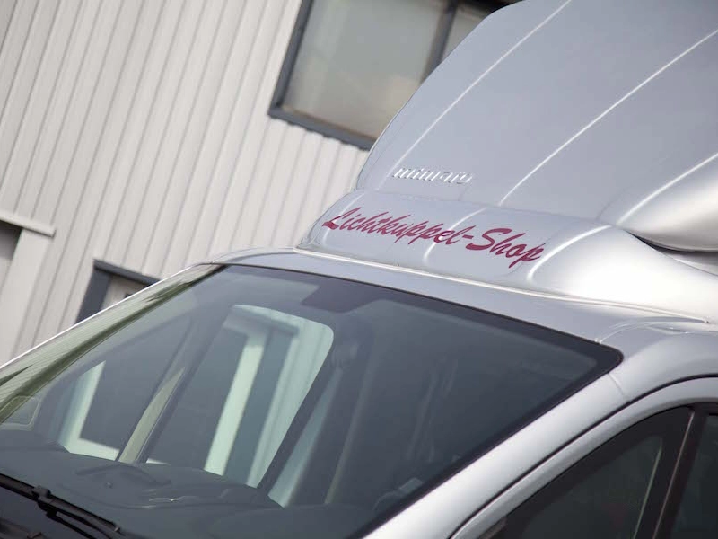 Nahaufnahme des Dachspoilers eines Transporters mit dem roten Schriftzug Lichtkuppel-Shop.