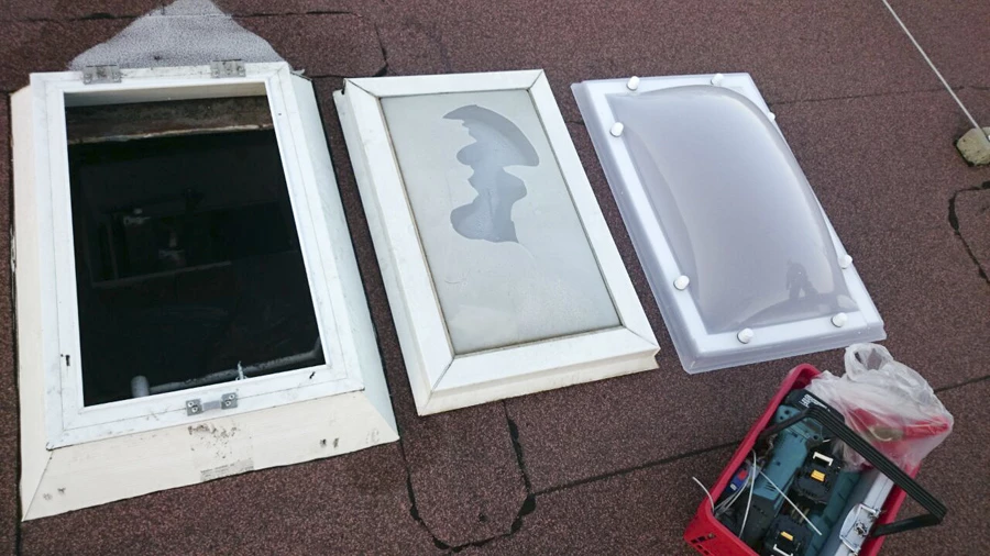 Auf dem Dach nebeneinander: der geöffnete Rahmen über dem Dachausschnitt, die ausgebaute vergilbte Acrylschale und die neue Oberschale.