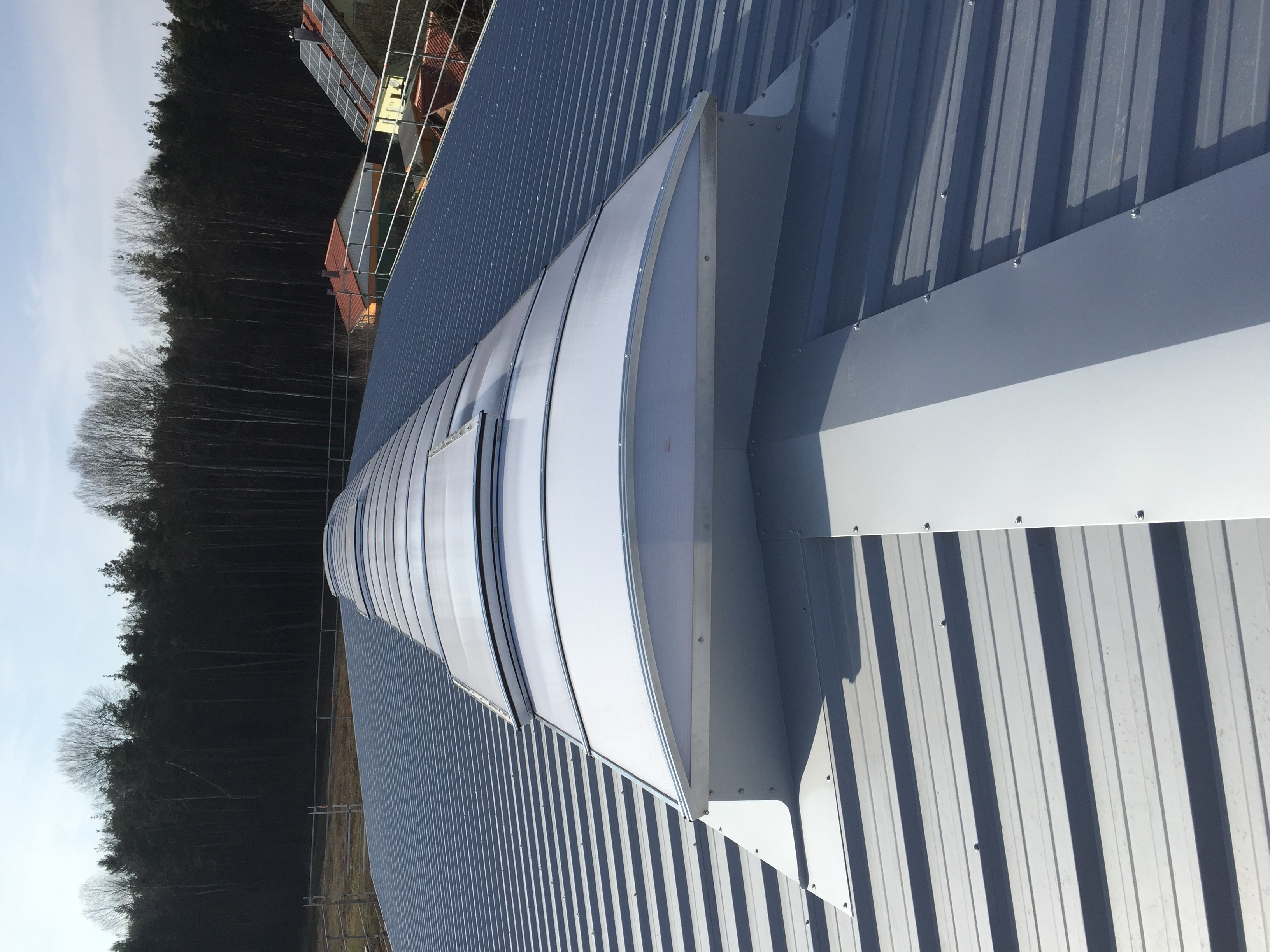 Firstlichtband aus Polycarbonat-Stegplatten auf dem First eines Trapezblechdachs, eine Klappe steht offen.