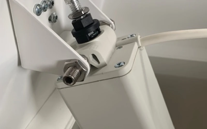 Nahaufnahme eines wei&szlig;en Spindelantriebs, der &uuml;ber einen verzinkten Beschlag am Rahmen der Lichtkuppel verschraubt ist.