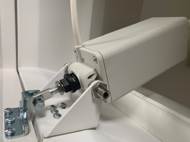 Nahaufnahme eines weißen Spindelantriebs, der über einen verzinkten Beschlag am Rahmen der Lichtkuppel verschraubt ist.