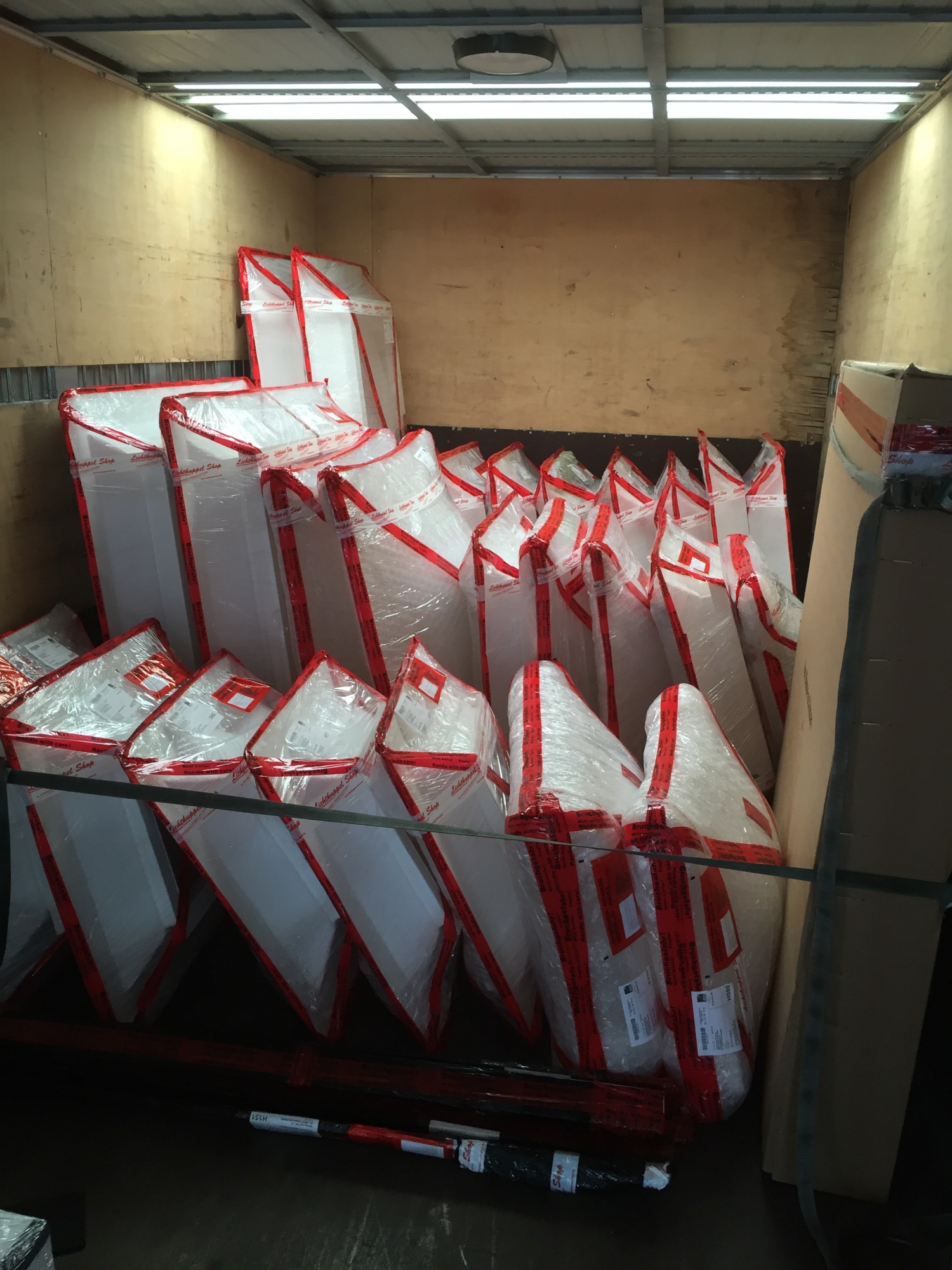 Beladener Lkw-Innenraum mit vielen rot-weiß verpackten Lichtkuppeln, hochkant gestellt und verzurrt.