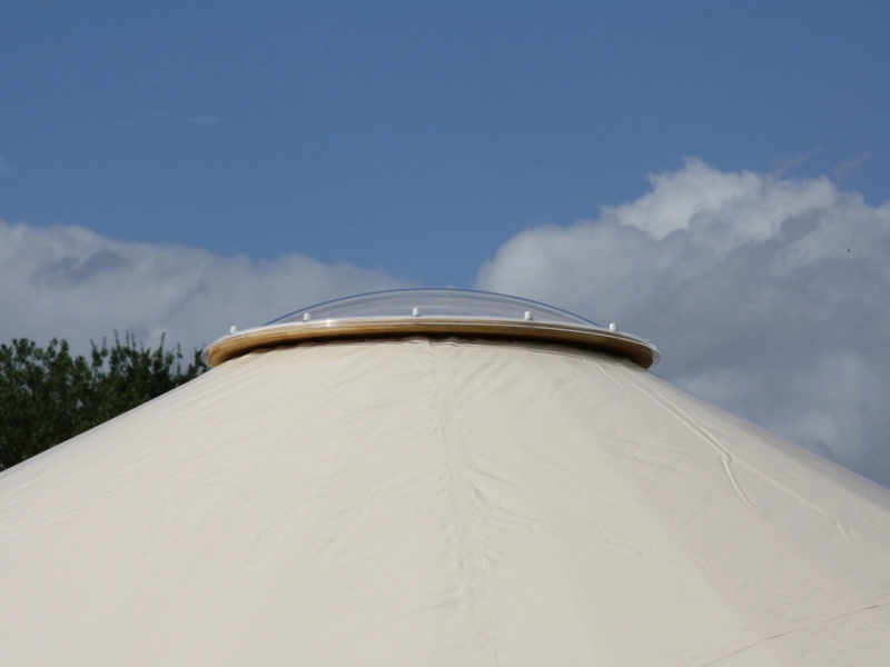 Nahaufnahme der Dachspitze von au&szlig;en: die klare Kuppel sitzt auf einem h&ouml;lzernen Ring &uuml;ber der Zeltplane.
