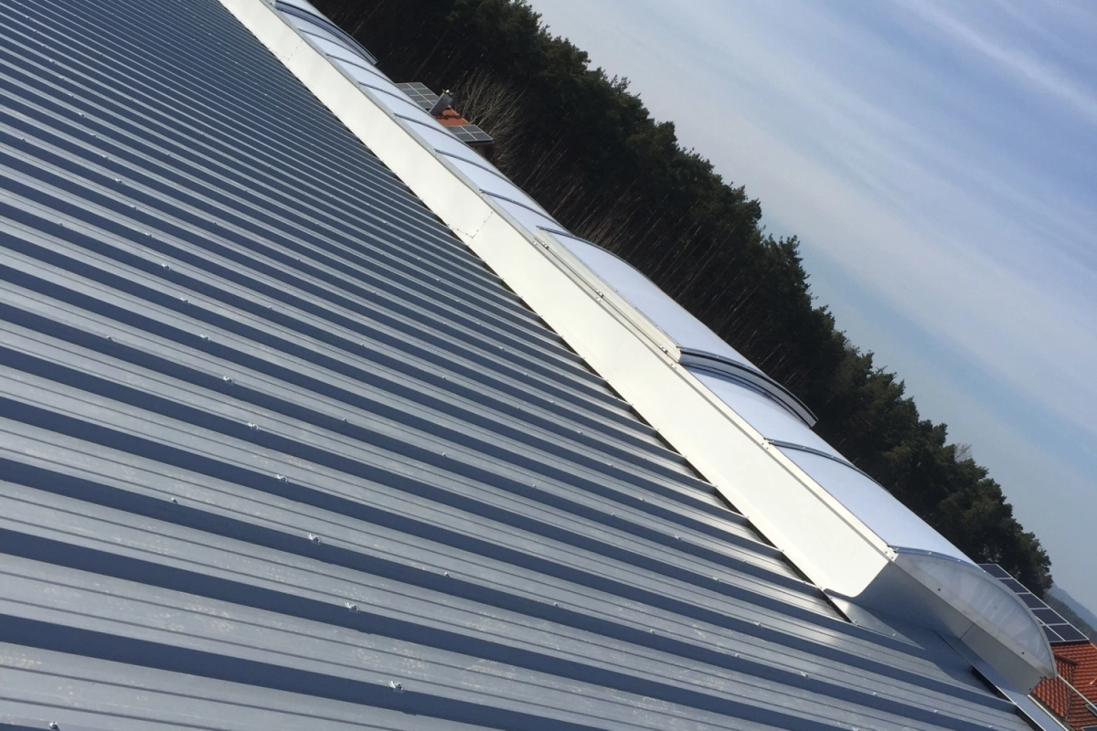 Das fertige Lichtband zieht sich in flachem Blickwinkel &uuml;ber den First, links und rechts f&auml;llt das Trapezblechdach ab.