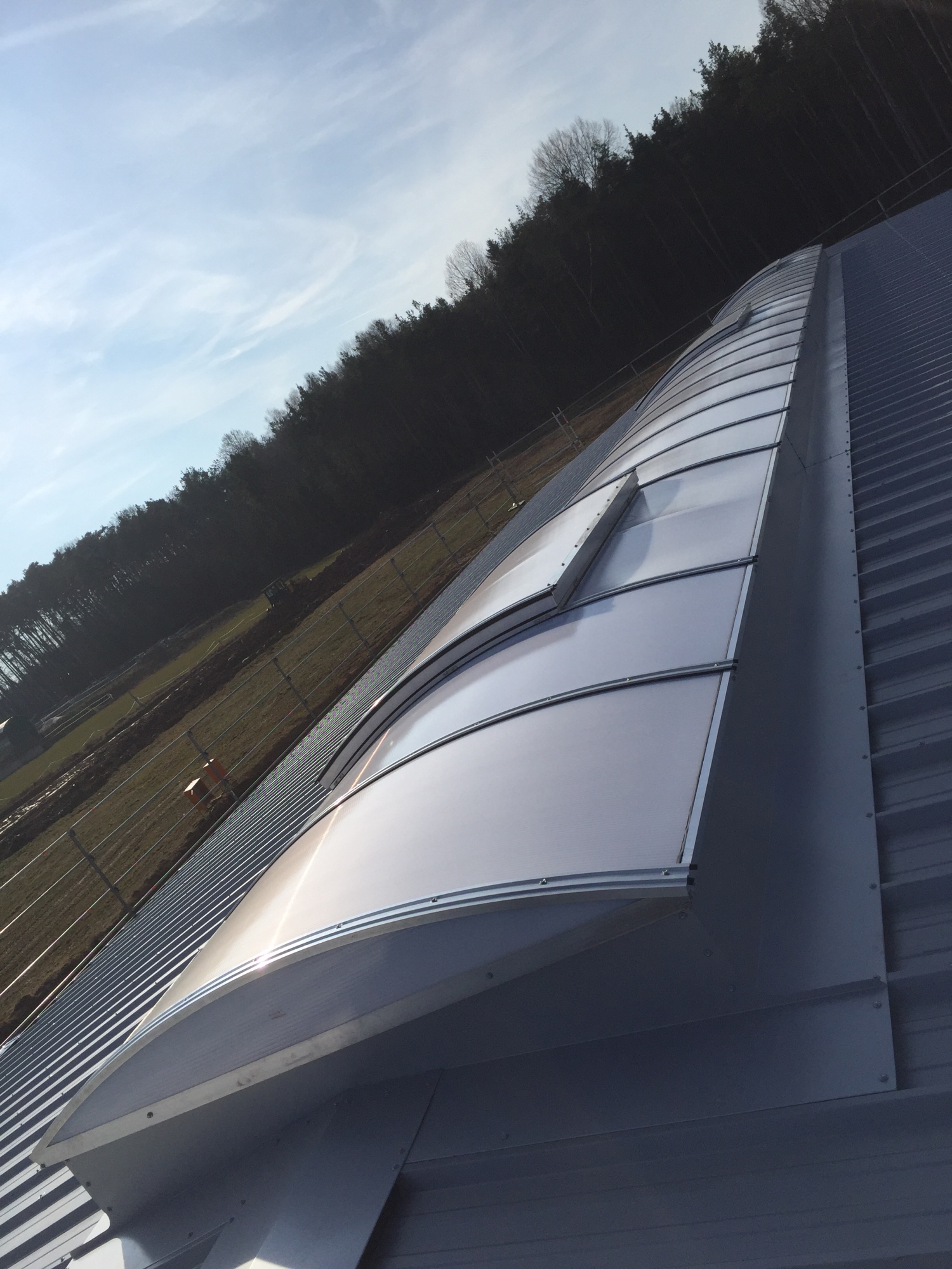 Das fertige Lichtband aus der Untersicht entlang der Dachkante, dahinter Feld und Waldrand.