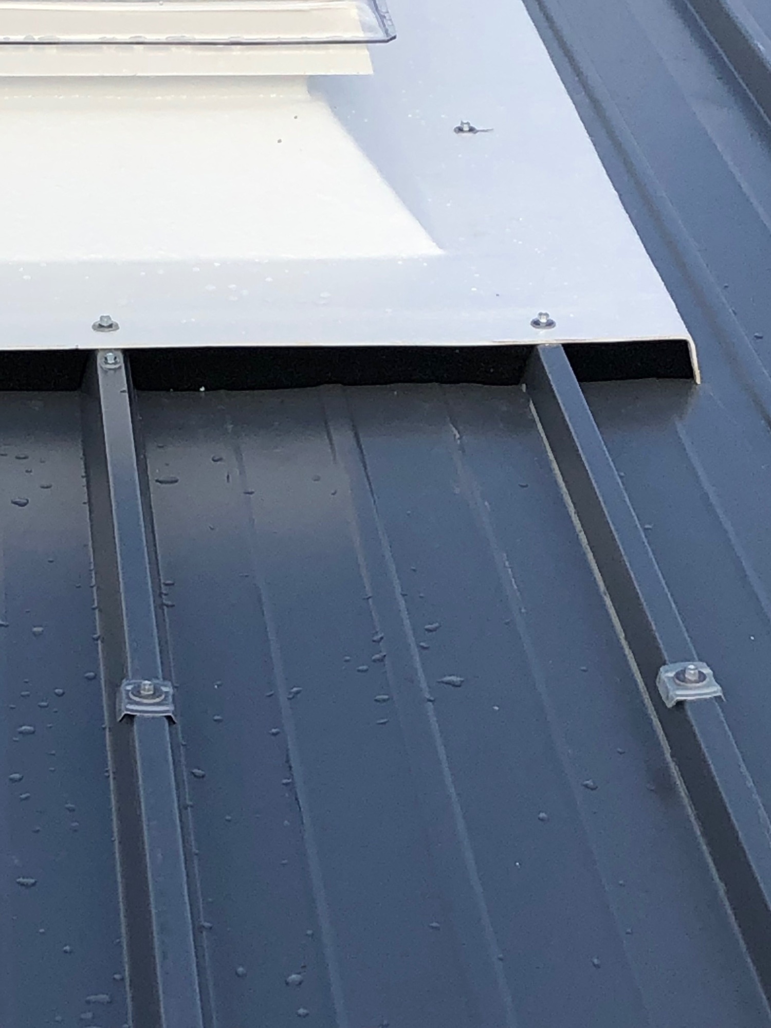 Detail des Anschlusses: Die abgekantete Blechschürze des Aufsatzkranzes liegt auf dem Trapezblech und ist verschraubt.
