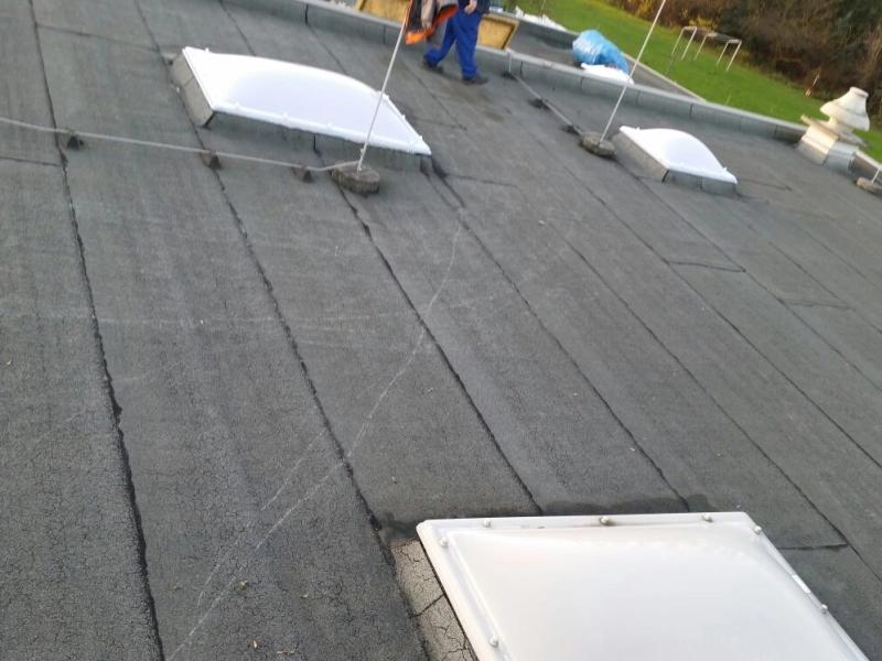 Dachfl&auml;che mit neuen Lichtkuppeln, am oberen Bildrand geht eine Person in Arbeitskleidung &uuml;ber das Dach.