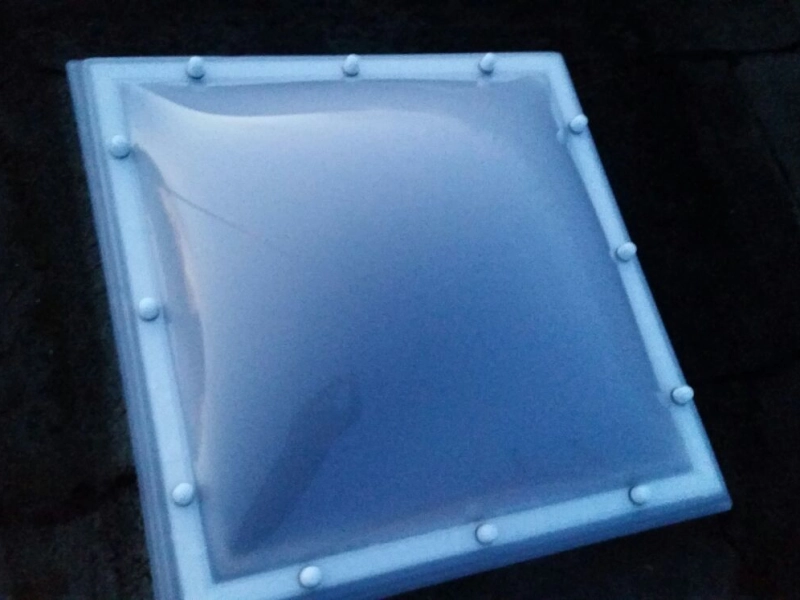 Nahaufnahme einer einzelnen neuen Lichtkuppel auf dunklem Bitumendach in der D&auml;mmerung.