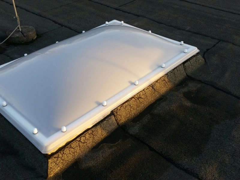 Nahaufnahme einer neuen wei&szlig;en Lichtkuppel auf einem aufgerauten Betonkranz, daneben ein Sicherungsseil.