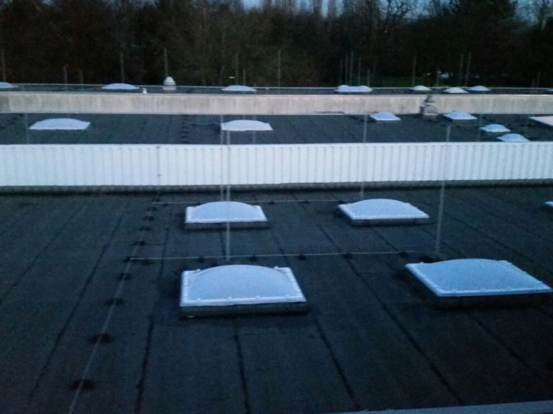 Dachfl&auml;che in der D&auml;mmerung mit neuen Lichtkuppeln beiderseits einer wei&szlig;en Attika.