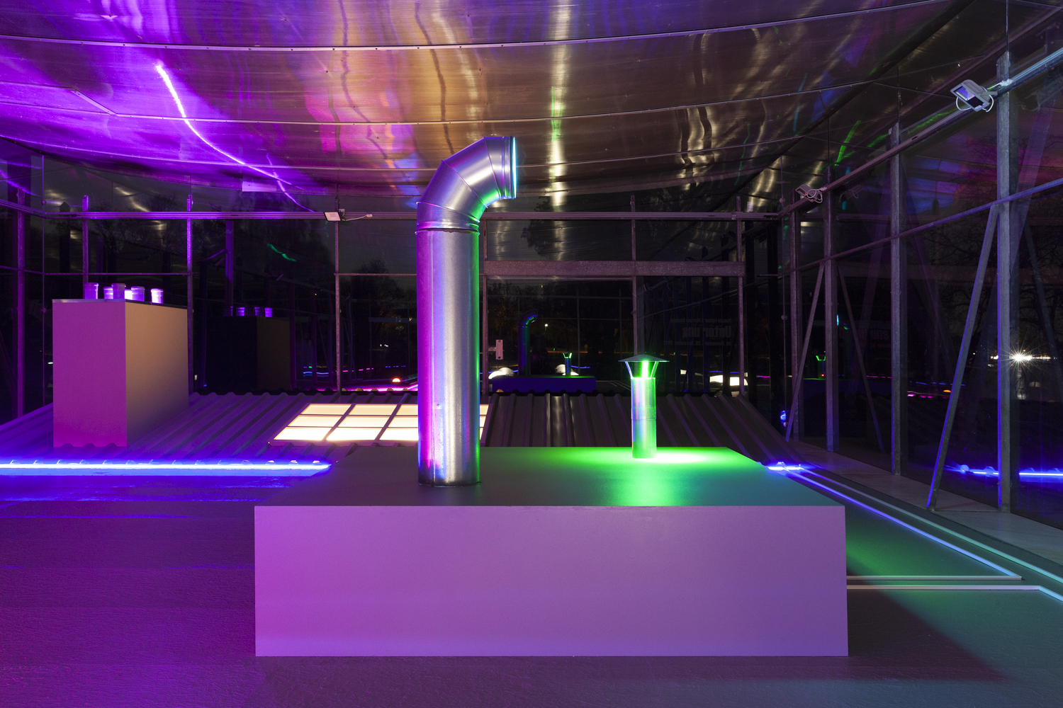 Blick auf ein Podest mit senkrechtem Lüftungsrohr, darüber die violett angestrahlte Deckenfolie des Pavillons.